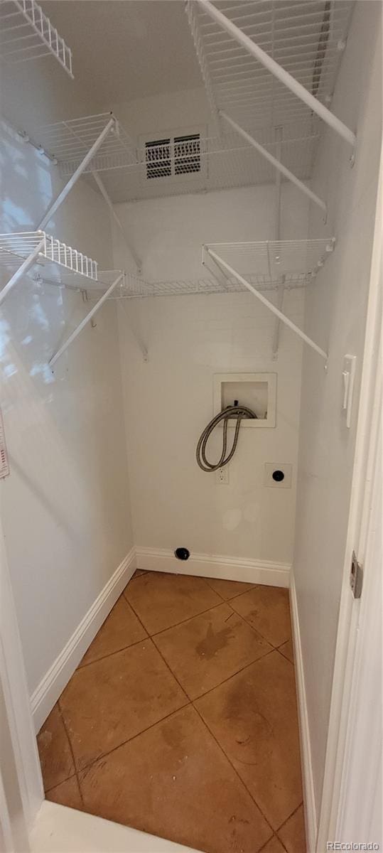 clothes washing area with hookup for an electric dryer, tile patterned flooring, and hookup for a washing machine