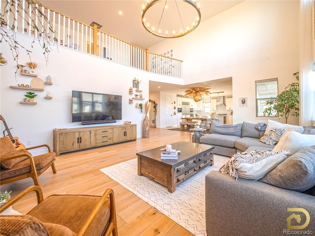 living area with recessed lighting, a notable chandelier, a high ceiling, and wood finished floors