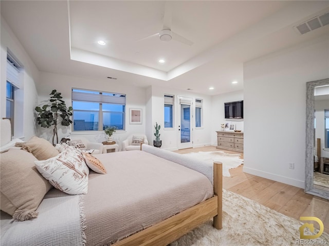 bedroom with a tray ceiling, recessed lighting, visible vents, wood finished floors, and access to outside