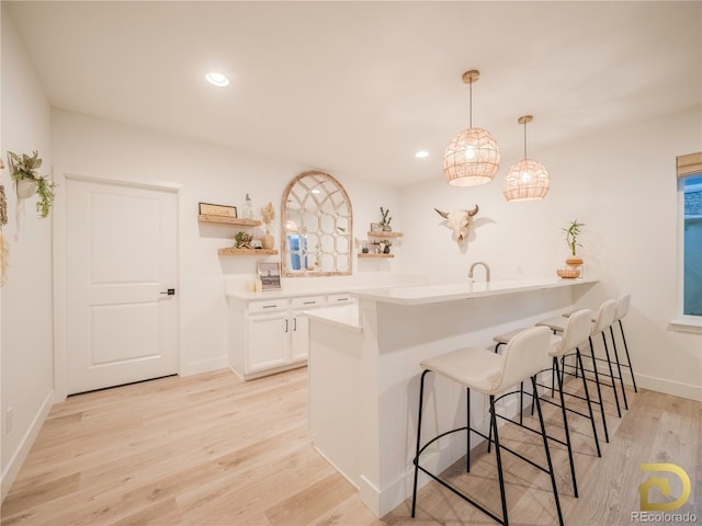 kitchen featuring white cabinets, decorative light fixtures, a peninsula, light countertops, and open shelves