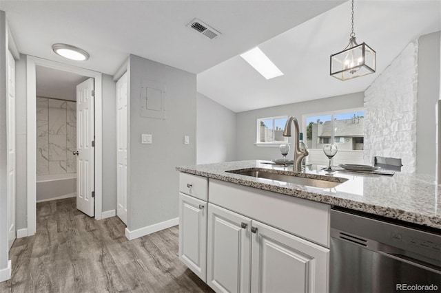 3100 S Federal Blvd Unit 331, Denver, CO 80236 - kitchen featuring stainless steel dishwasher, a sink, light wood-style flooring, light stone countertops, and white cabinetry