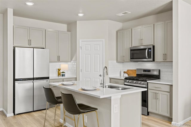 762 N Rome St, Aurora, CO 80018 - kitchen with appliances with stainless steel finishes, a sink, light wood-style flooring, light countertops, and tasteful backsplash