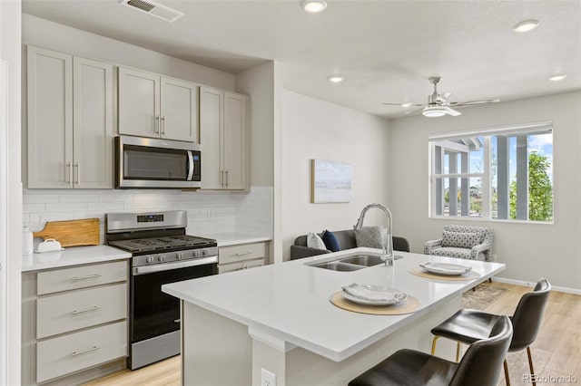 762 N Rome St, Aurora, CO 80018 - kitchen featuring appliances with stainless steel finishes, a sink, backsplash, light wood-style flooring, and a ceiling fan