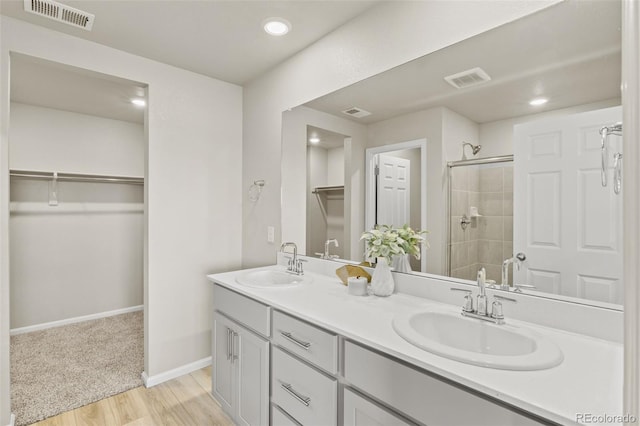 762 N Rome St, Aurora, CO 80018 - bathroom with a shower stall, a walk in closet, wood finished floors, double vanity, and baseboards