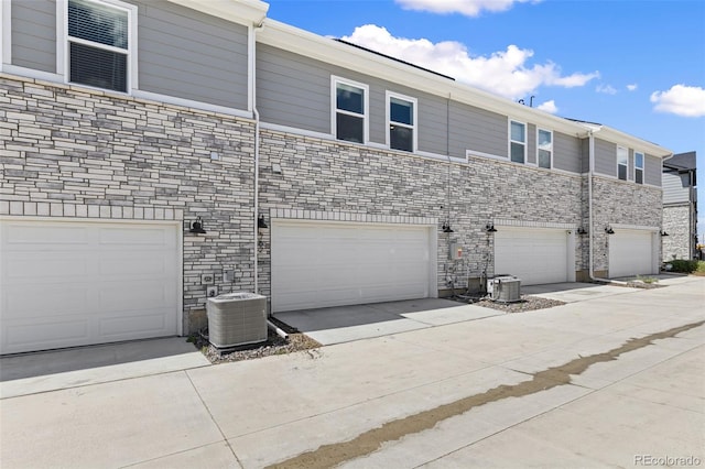 762 N Rome St, Aurora, CO 80018 - view of front of house featuring central air condition unit, stone siding, and a garage