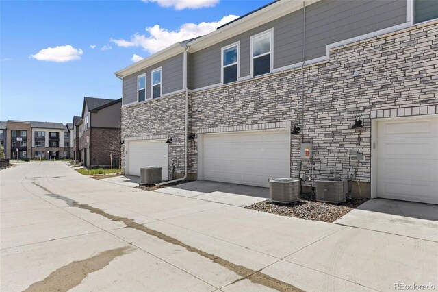 762 N Rome St, Aurora, CO 80018 - view of property exterior with stone siding, a garage, central air condition unit, and concrete driveway