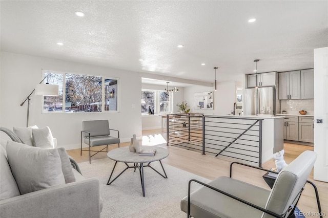 living room with light hardwood / wood-style flooring, sink, a wealth of natural light, and a textured ceiling