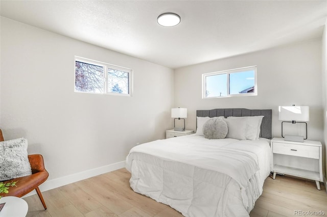 bedroom with light hardwood / wood-style floors and multiple windows