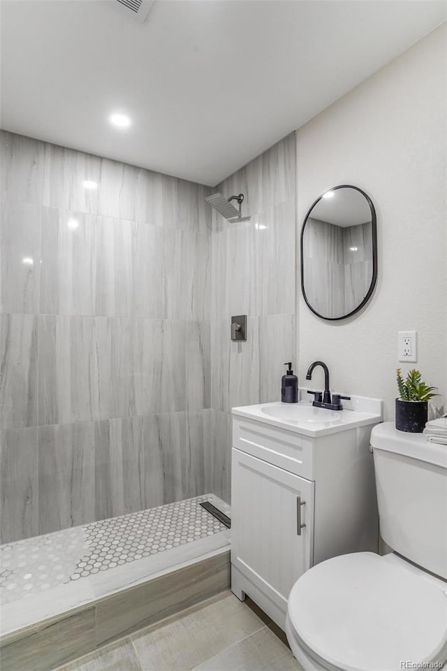 bathroom with vanity, toilet, and a tile shower