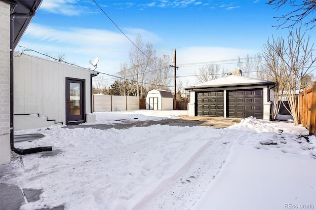 snowy yard with a shed and a garage