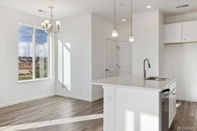 kitchen featuring a chandelier, white cabinetry, a center island with sink, and pendant lighting