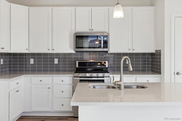 kitchen featuring appliances with stainless steel finishes, backsplash, white cabinetry, and hanging light fixtures