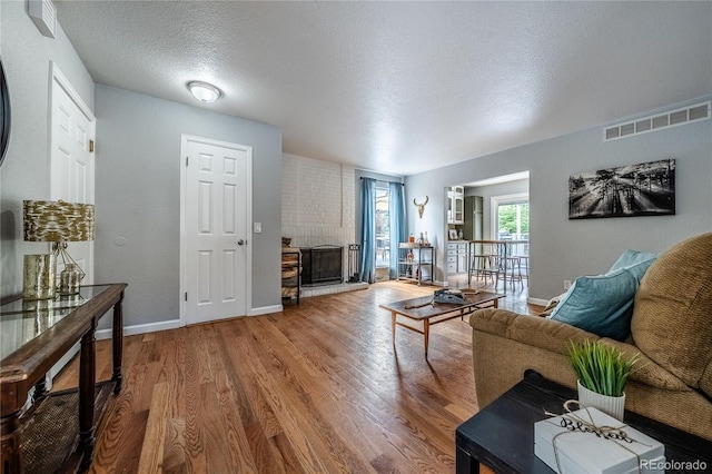 4571 S Memphis St, Aurora, CO 80015 - living room with wood finished floors, a brick fireplace, baseboards, and a textured ceiling