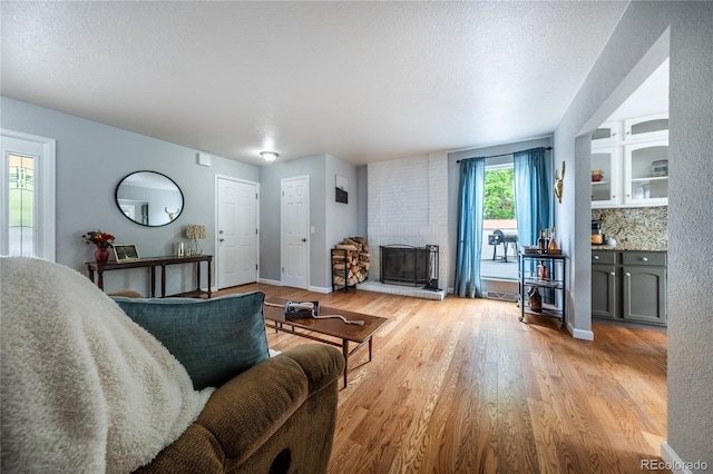 4571 S Memphis St, Aurora, CO 80015 - living room featuring a brick fireplace, light wood-style floors, and baseboards
