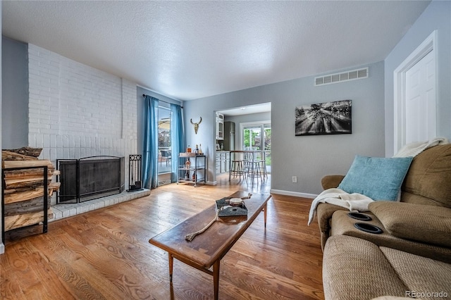 4571 S Memphis St, Aurora, CO 80015 - living room with wood finished floors, a brick fireplace, a textured ceiling, and baseboards