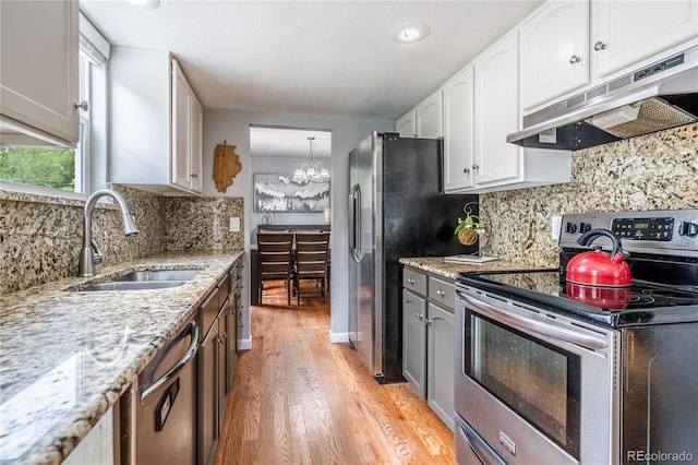 4571 S Memphis St, Aurora, CO 80015 - kitchen featuring stainless steel appliances, under cabinet range hood, a sink, light wood finished floors, and white cabinetry