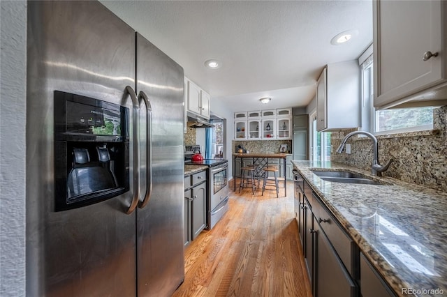 4571 S Memphis St, Aurora, CO 80015 - kitchen featuring appliances with stainless steel finishes, light wood-style floors, light stone countertops, and a sink