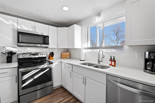 kitchen with appliances with stainless steel finishes, dark hardwood / wood-style floors, sink, white cabinets, and decorative backsplash