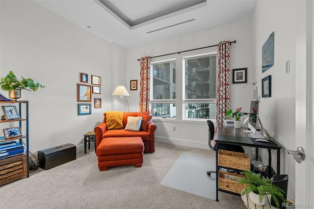 office space featuring a tray ceiling and light carpet