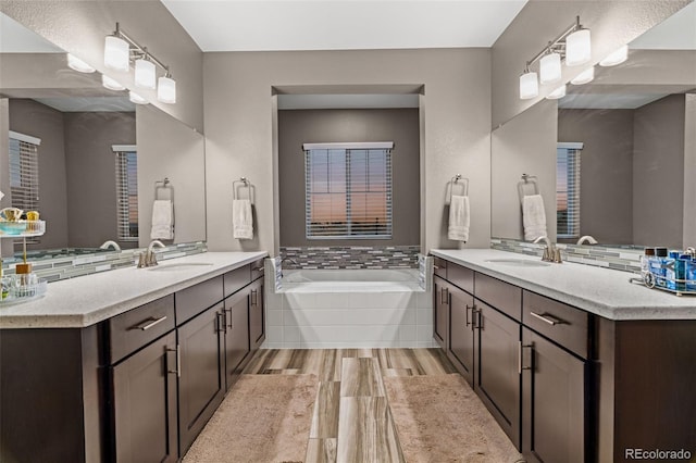 bathroom featuring hardwood / wood-style flooring, vanity, and a relaxing tiled tub