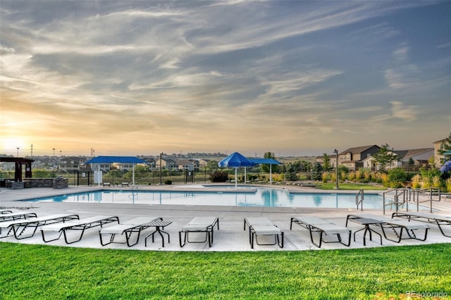 pool at dusk featuring a yard