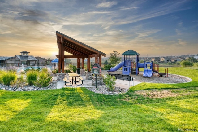 playground at dusk with a patio area and a yard