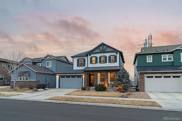 view of front facade featuring covered porch, a standing seam roof, a garage, stone siding, and driveway