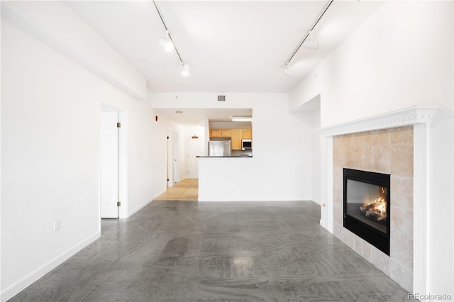 1780 N Washington St Unit 305, Denver, CO 80203 - unfurnished living room with rail lighting, a tile fireplace, baseboards, and finished concrete flooring