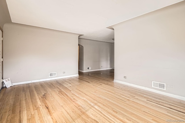 unfurnished room featuring visible vents, baseboards, and wood finished floors