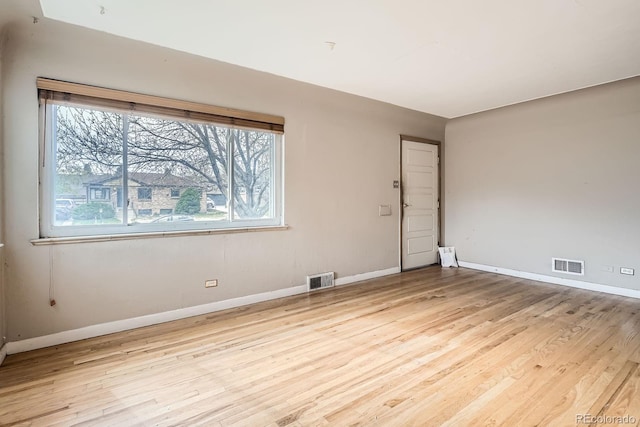 empty room featuring light wood-style floors, baseboards, and visible vents