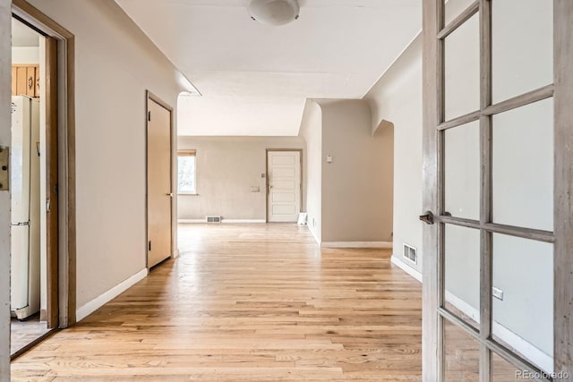 hall with visible vents, light wood finished floors, and baseboards