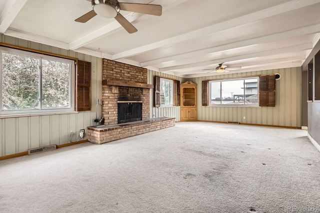 unfurnished living room featuring a fireplace, carpet floors, beamed ceiling, and a ceiling fan