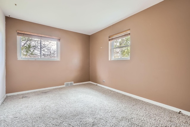 empty room featuring carpet floors, baseboards, and visible vents