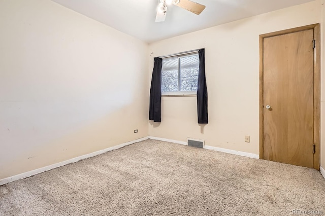 carpeted spare room with visible vents, baseboards, and ceiling fan