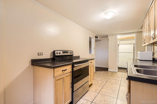 kitchen with freestanding refrigerator, dark countertops, a sink, and electric stove