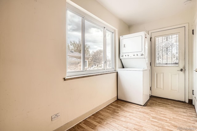 laundry room featuring light wood-style floors, baseboards, stacked washer and clothes dryer, and laundry area