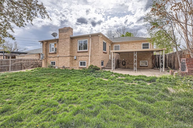 back of house with brick siding, a fenced backyard, a chimney, a patio area, and a lawn