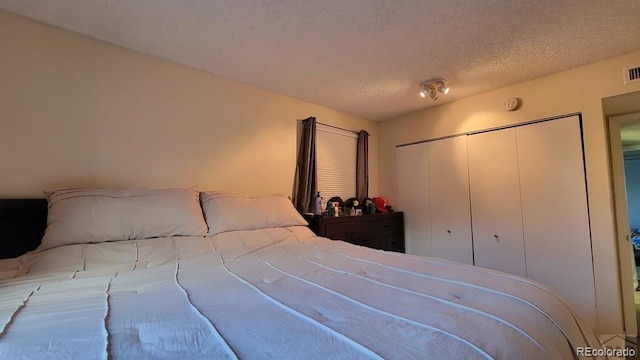bedroom featuring a textured ceiling, a closet, and visible vents