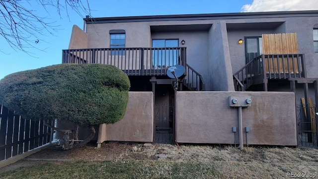 rear view of house featuring stucco siding, a gate, stairway, and a fenced front yard