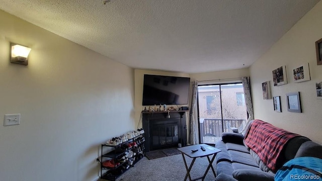 living area featuring a textured ceiling, a glass covered fireplace, and carpet floors