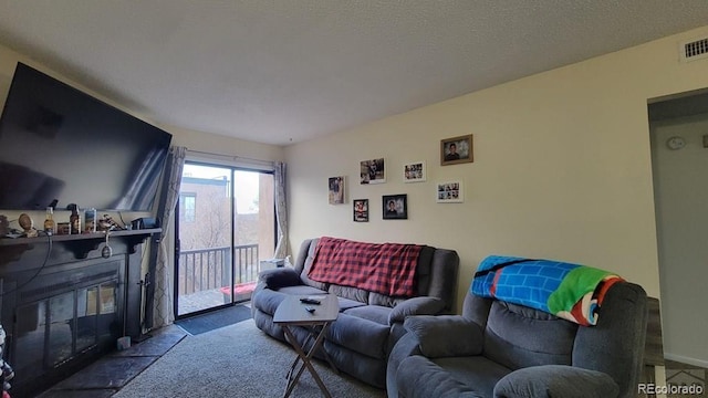 living area featuring a textured ceiling and a glass covered fireplace