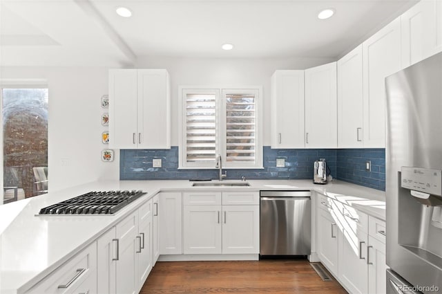 kitchen with stainless steel appliances, light countertops, a sink, and dark wood-style floors