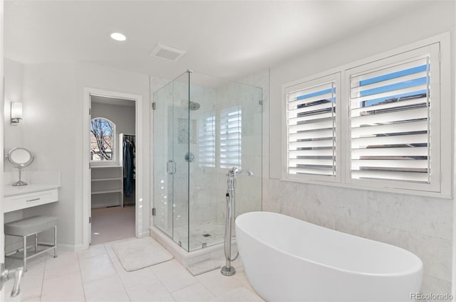 full bath featuring visible vents, a spacious closet, a soaking tub, a shower stall, and tile patterned floors