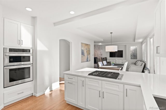 kitchen with open floor plan, double oven, light countertops, and white cabinetry