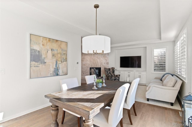 dining area with light wood-type flooring, a fireplace, and baseboards