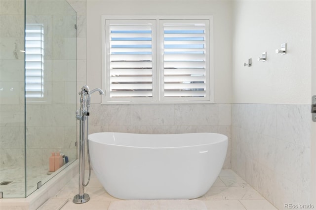 full bath featuring plenty of natural light, tile walls, a freestanding bath, and a shower stall