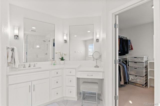 bathroom featuring a stall shower, a walk in closet, and vanity