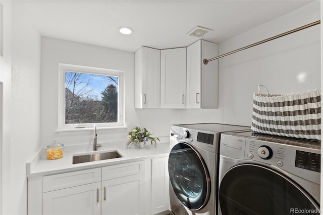 washroom with cabinet space, visible vents, a sink, and separate washer and dryer