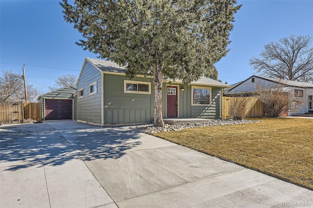 ranch-style home with a garage, concrete driveway, fence, board and batten siding, and a front yard