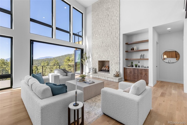 13415 S Resort Dr, Conifer, CO 80433 - living area with a high ceiling, built in shelves, plenty of natural light, a stone fireplace, and light wood-style flooring